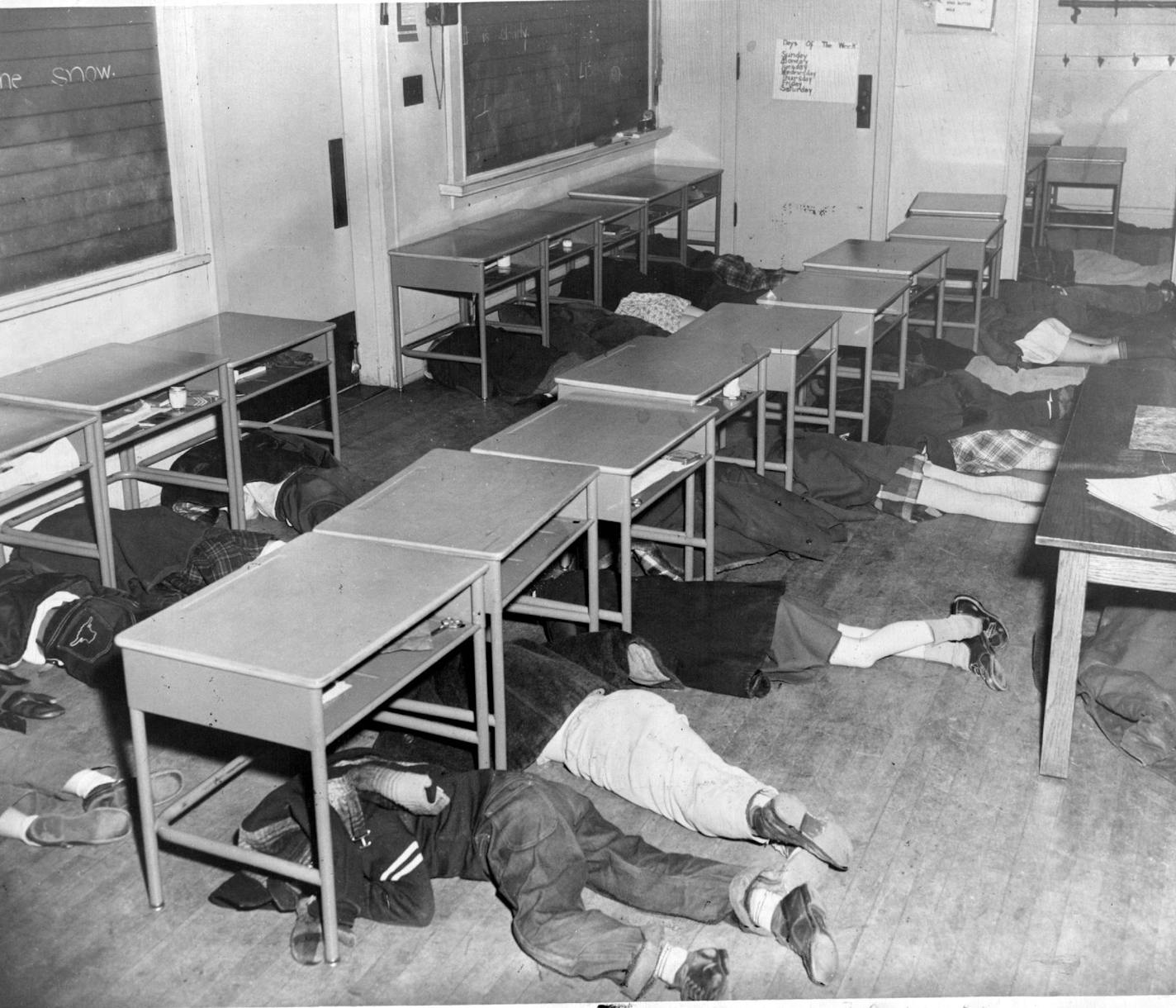 May 26, 1957 Minneapolis Pupils Duck Under Desks At Sound Of Siren For many it's a frightening experience The first grader you saw on page one, crouching calMinneapolis Star Libraryy under his desk, is taking proper cover in the Minneapolis public schools' first complete atomic bomb raid practice Thursday. The drills were held at the Harrison school, with only one room participating, and at Holmes school, Fifth street and Third avenue SE&#xe2;&#x20ac;&#x17e; where the entire school took part. Sh