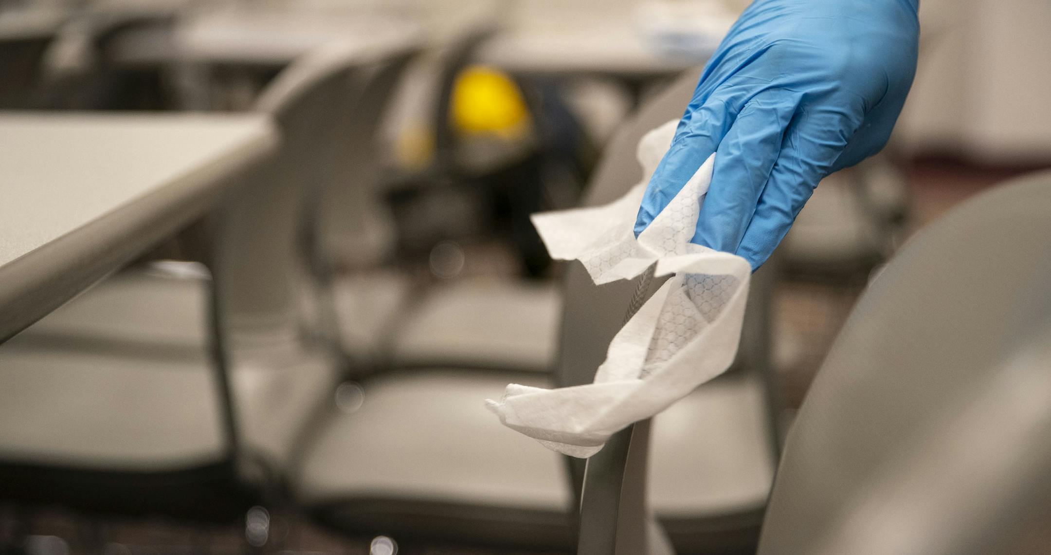 Lorenze Hoss, a freshman international student from Germany, disinfected chairs and tables in a classroom on Wednesday. ] ALEX KORMANN • alex.kormann@startribune.com The College of St. Scholastica buildings and ground team were have been hard at work for days deep cleaning and sanitizing classrooms and apartment rooms around the school.