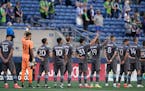 Minnesota United's Dayne St. Clair (97), Hassani Dotson (31), and Romain Metanire (19) raise their fists during the national anthem before the team's 