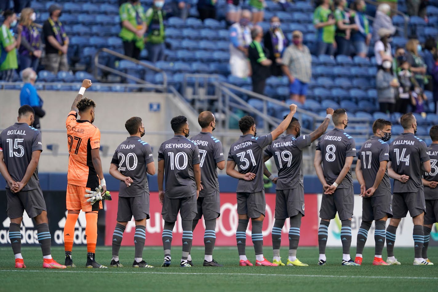 Minnesota United's Dayne St. Clair (97), Hassani Dotson (31), and Romain Metanire (19) raise their fists during the national anthem before the team's match against the Seattle Sounders