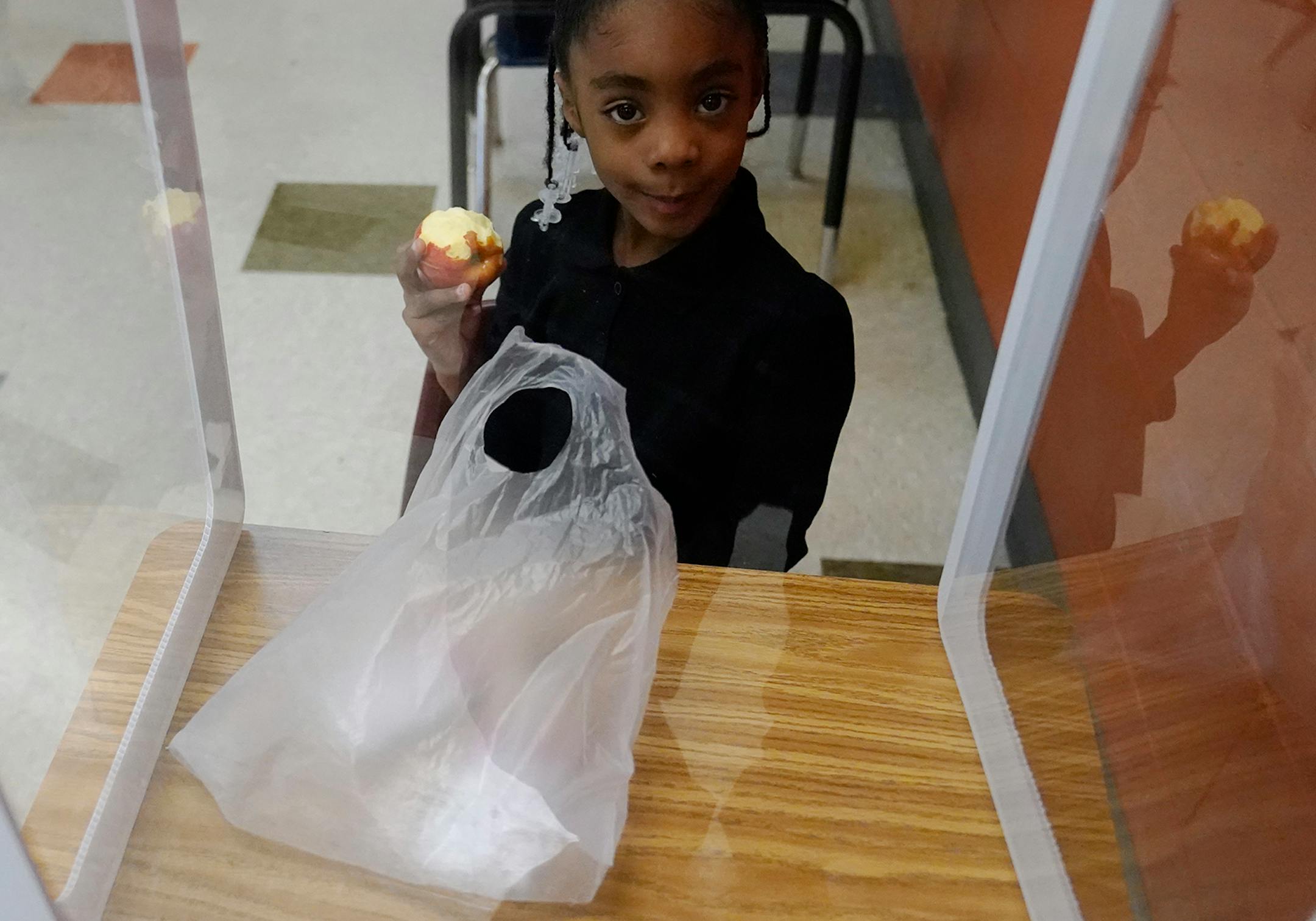 It was back to school for some students at Harvest Best Academy Tuesday in Minneapolis, but with masks, plastic barriers and other new precautions in the era of COVID-19. Here, a Harvest Best Academy kindergarten pupil ate an apple from her protective desk during lunch time in a kindergarten learning pod.