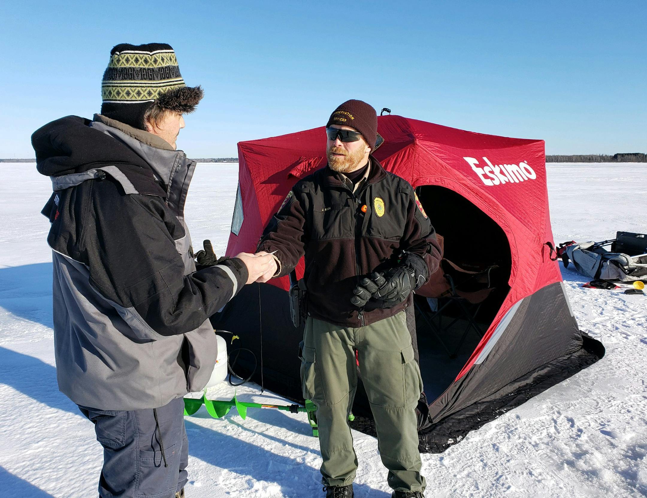 Conservation officer Jim Guida, right, checked the fishing license of Dan Curtis of Mankato. They were on Lake Edward.