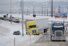 A tow truck, right, pulls up to clear a tractor-trailer and sports utility vehicle stuck in snow on an off ramp off Interstate 70 as a winter storm pa