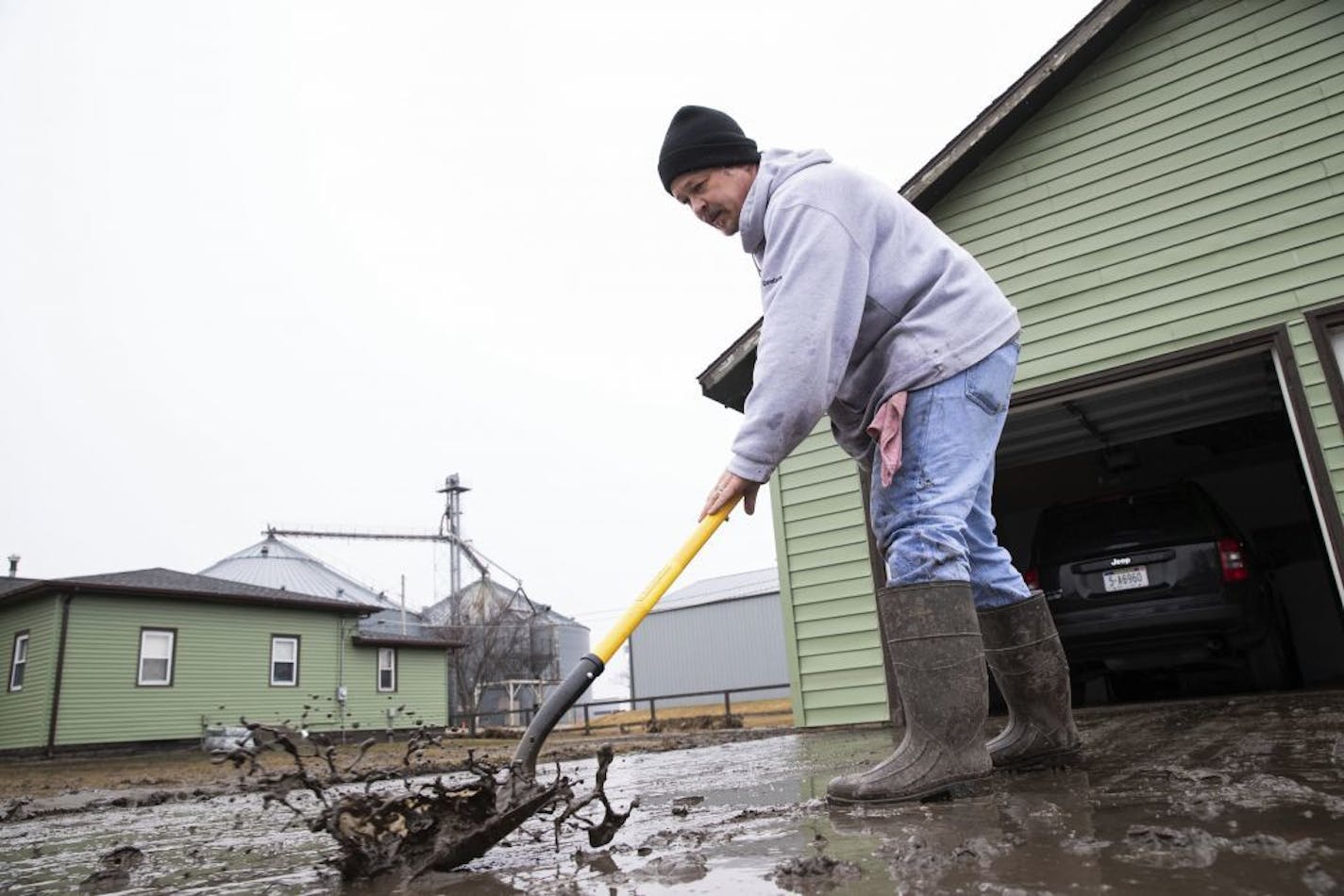 Mike Loeffler clears mud from his driveway on Willow Street while dealing with the aftermath of major flooding Tuesday, March 19, 2019, in North Bend, Neb. The president of the Nebraska Farm Bureau says farm and ranch losses due to the devastating flooding could reach $1 billion in the state