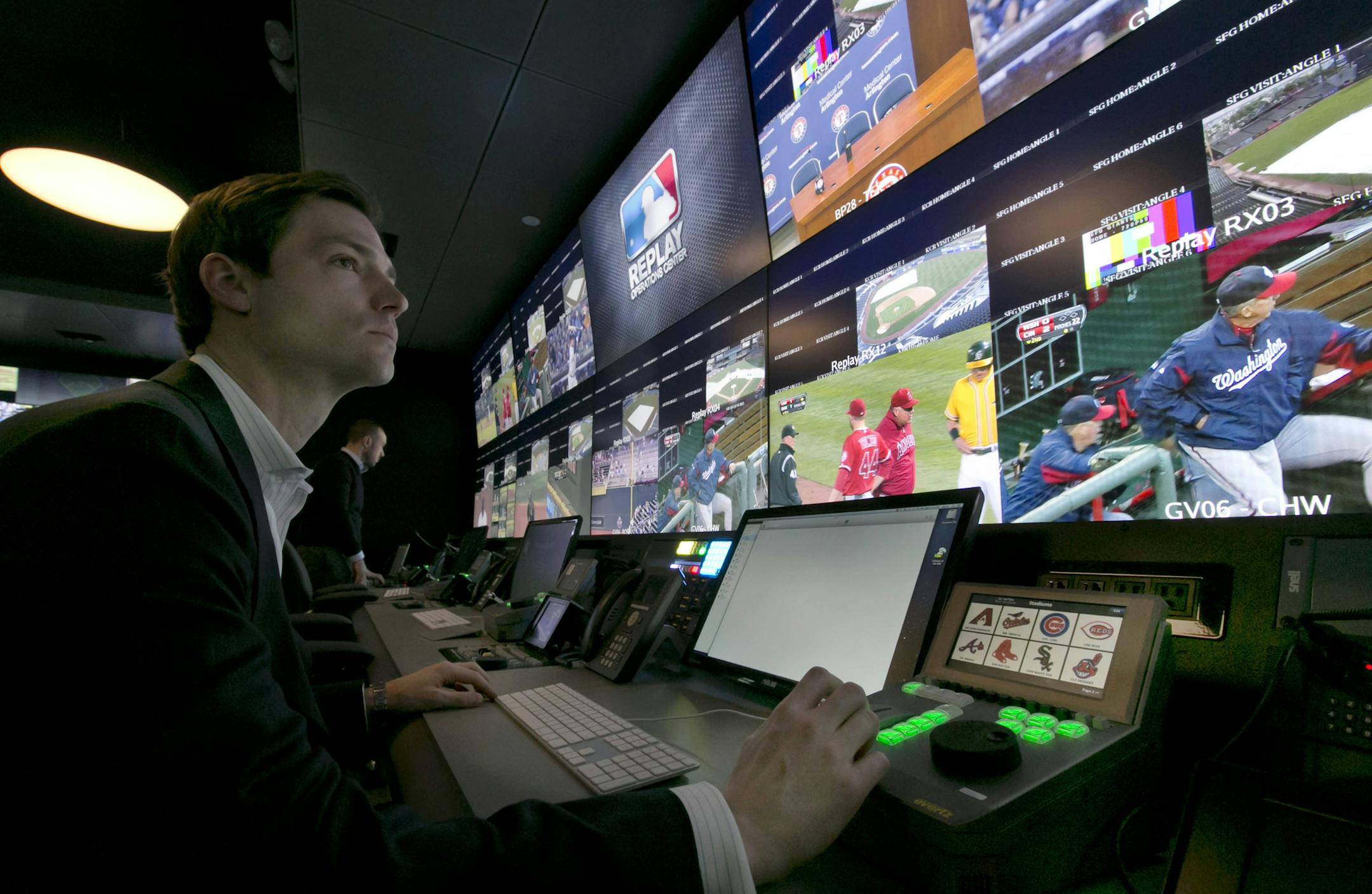 Chris Marinak sits in front of a bank of television screens during a preview of Major League Baseball's Replay Operations Center, in New York, Wednesday, March 26, 2014. Less than a week before most teams open, MLB is working on the unveiling of its new instant replay system, which it hopes will vastly reduce incorrect calls by umpires. (AP Photo/Richard Drew)