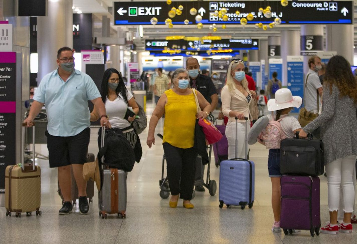 Travelers wearing protective face masks walking through Concourse D at the Miami International Airport on Sunday, November 22, 2020 in Miami, Florida. With the coronavirus surging out of control, the nation's top public health agency pleaded with Americans not to travel for Thanksgiving and not to spend the holiday with people from outside their household.