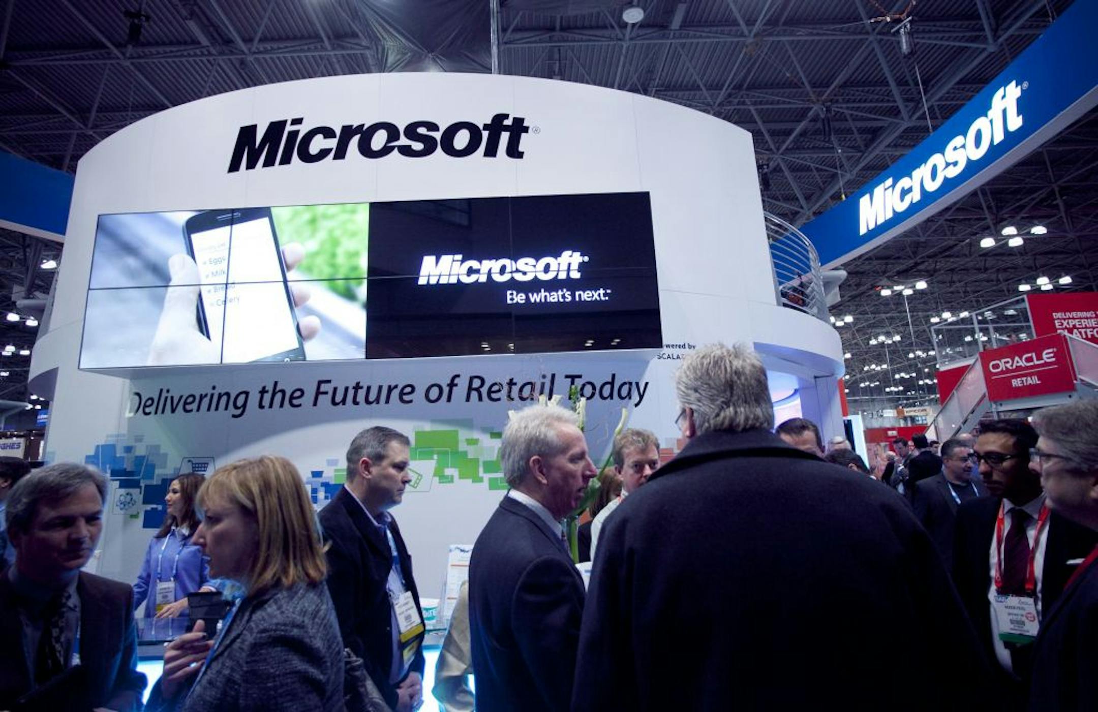 Attendees at the National Retail Federation visit a Microsoft display, Tuesday, Jan. 17, 2012 in New York.