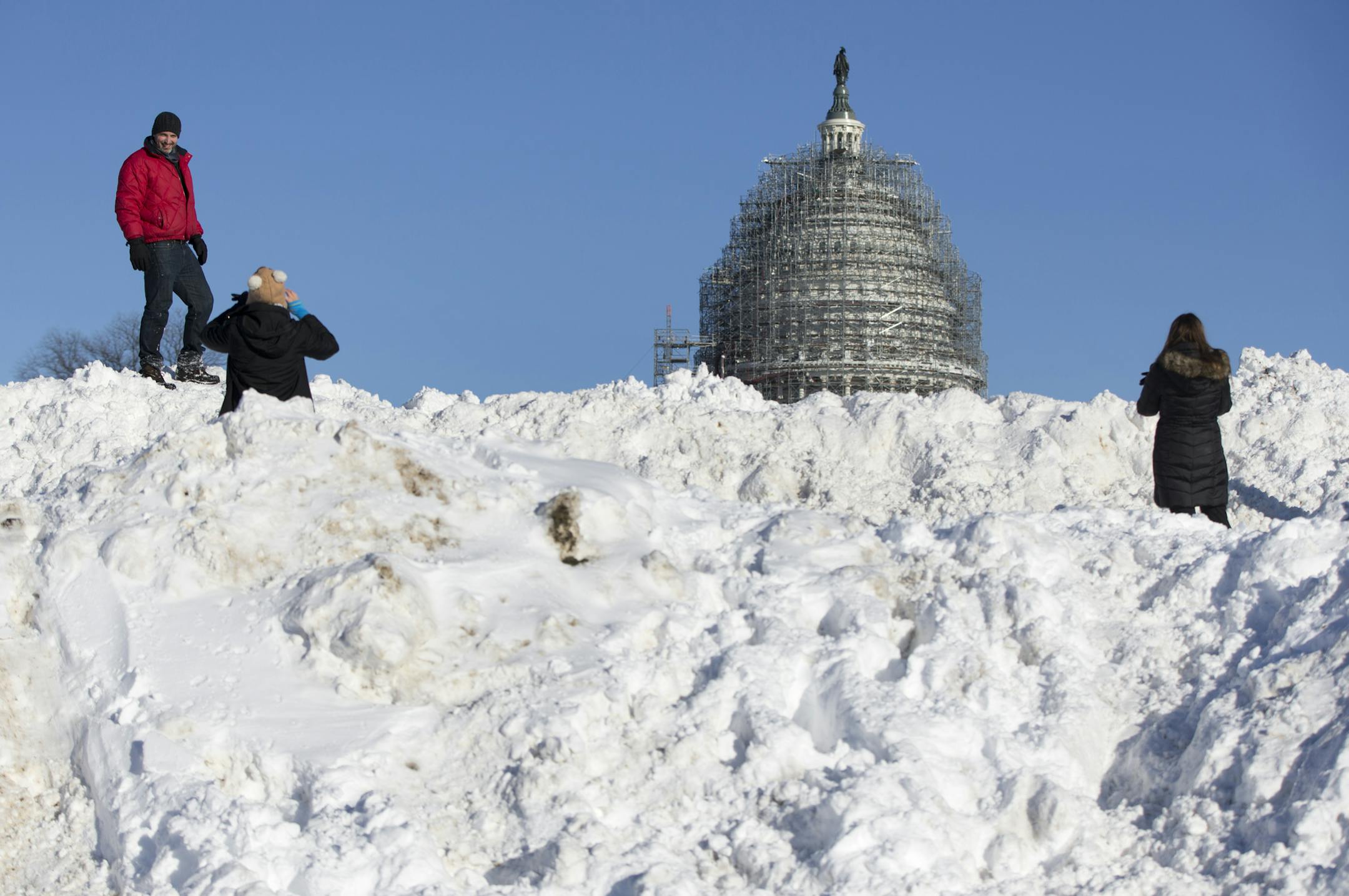 People take photographs atop a huge pile of snow in front of the U.S. Capitol Building in Washington, Sunday, Jan. 24, 2016. Washington is digging out after a mammoth blizzard with hurricane-force winds and record-setting snowfall brought much of the East Coast to an icy standstill. (AP Photo/Carolyn Kaster)