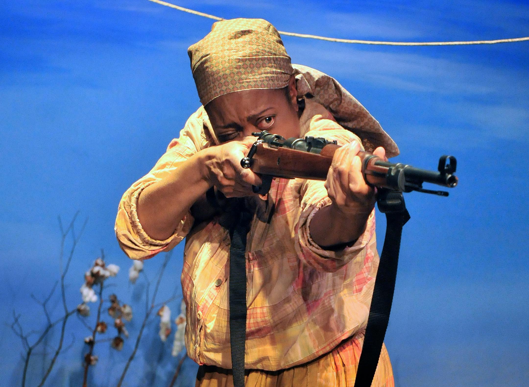 In the play "Scapegoat", Actor, Regina Marie Williams, Arkansas. Black sharecroppers Effie, points a rifle over the crowd at her counterpart in the play,Ora, played by Jennifer Blagen, her neighbor who was standing in the back of the house at the Pillsbury House Theater, Chicago Ave. Photo by George Byron Griffiths [ written by Christina M. Ham, directed by Marion McClinton, "Scapegoat". The small town of Elaine is the flashpoint for this tale of social and racial unrest in 1919 Arkansas. Black