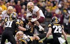 Minnesota running back Ky Thomas (8) leaps between Iowa linebacker Jack Campbell (31) and defensive back Jack Koerner (28) during the first half of an