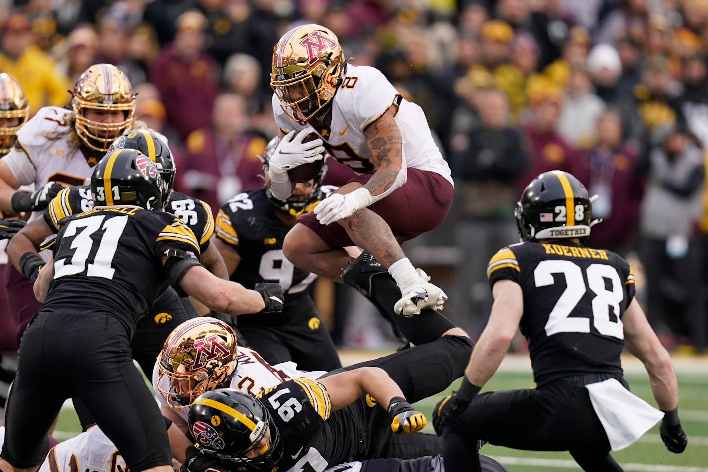 Minnesota running back Ky Thomas (8) leaps between Iowa linebacker Jack Campbell (31) and defensive back Jack Koerner (28) during the first half of an NCAA college football game, Saturday, Nov. 13, 2021, in Iowa City, Iowa. (AP Photo/Charlie Neibergall)