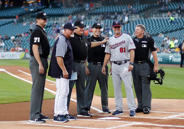 Detroit Tigers manager Ron Gardenhire poses with his son, Minnesota Twins' Toby Gardenhire and umpires, before a baseball game in Detroit, Monday, Sep