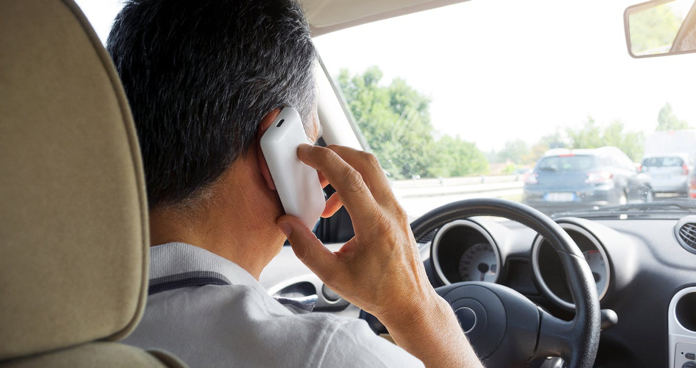 Man on the phone driving a car on highway.