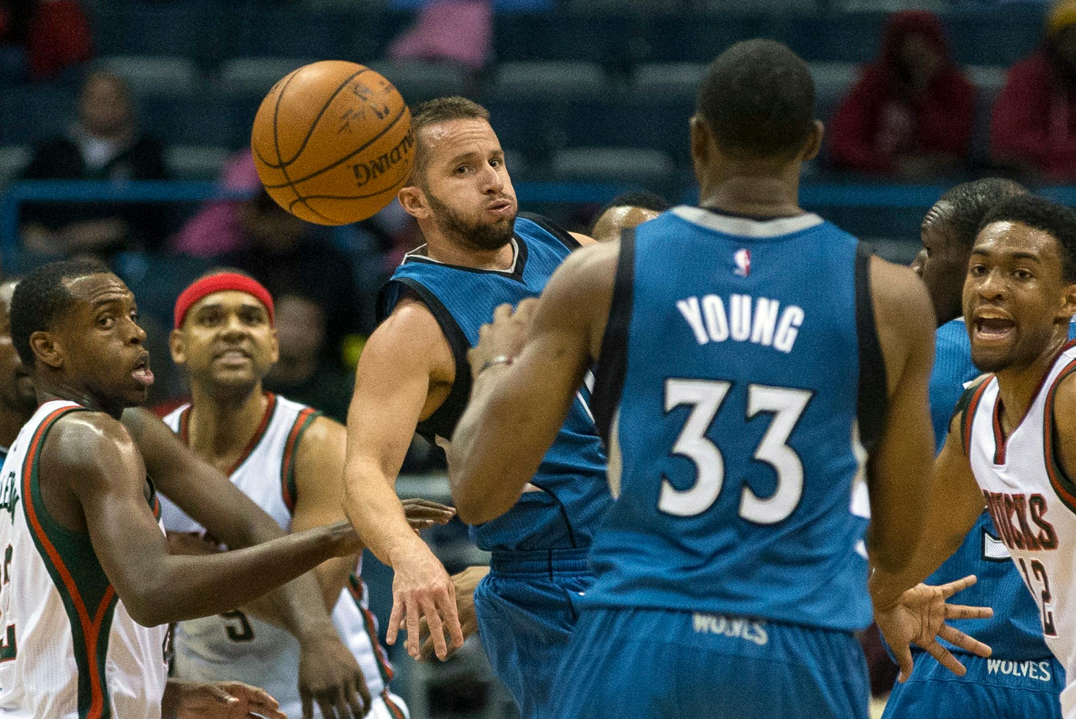 Milwaukee Bucks' Khris Middleton, left, watches the ball as Minnesota Timberwolves' J.J. Barea, center, passes back to teammate Thaddeus Young (33) during the first half of an NBA basketball game Wednesday, Oct. 22, 2014, in Milwaukee. (AP Photo/Tom Lynn)