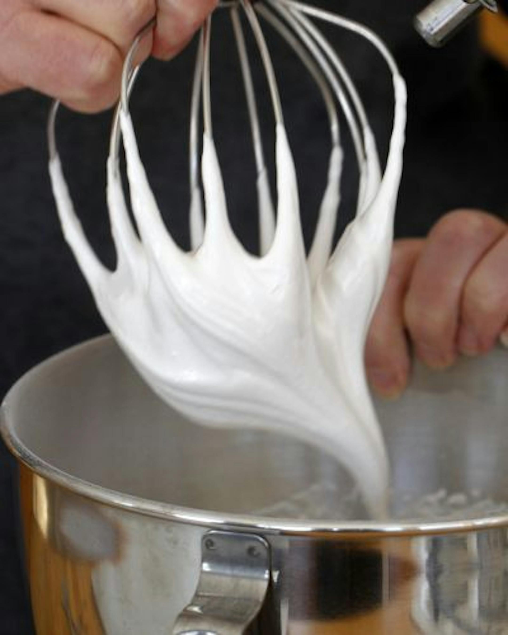 The egg whites are whipped with sugar until they hold a still peak when the beater is lifted.