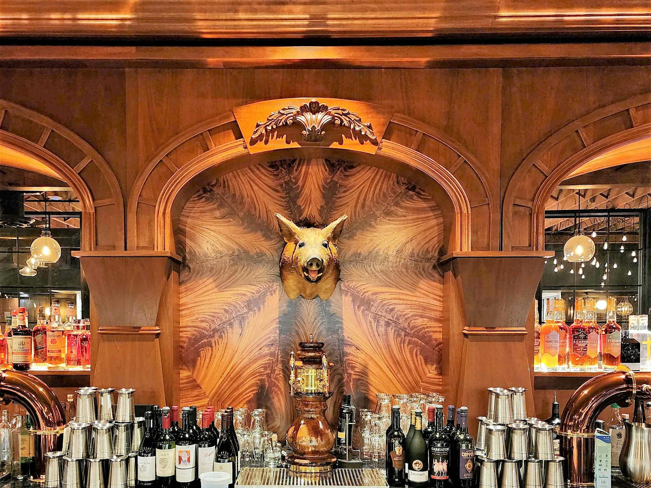 A bar with a boar's head and a warm glow inside the new Butcher &amp; The Boar