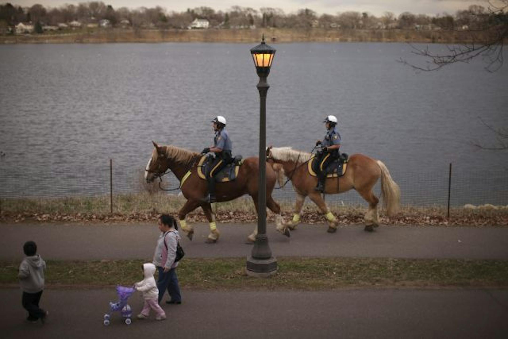 St. Paul Police Mounted Officers Gerry Johnson and Houa Vang, right, brought up the rear behind the large group that took part in the first "Walk With Cops" Wednesday night at Lake Phalen. They're riding Belgian Draft Horses named Chase and King.
