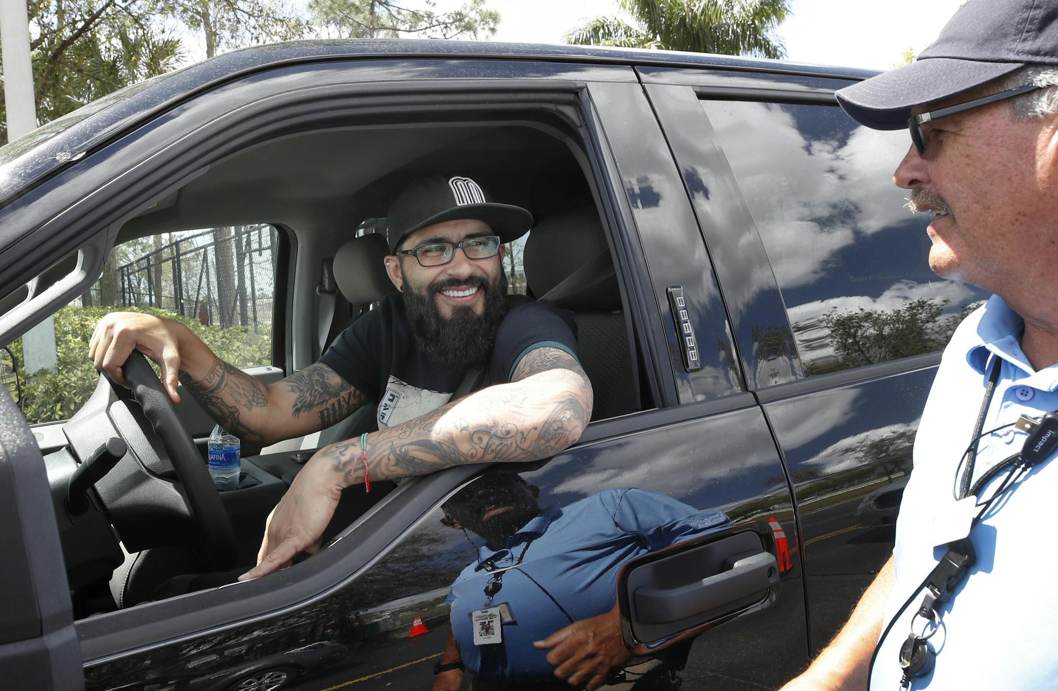 Minnesota Twins pitcher Sergio Romo stops to say goodbye to parking operations worker Bill Fear, as he drives out of Hammond Stadium, Saturday, March 14, 2020, in Fort Myers, Fla. Major League Baseball has suspended the rest of its spring training game schedule because of the coronavirus outbreak. MLB is also delaying the start of its regular season by at least two weeks. (AP Photo/Elise Amendola)