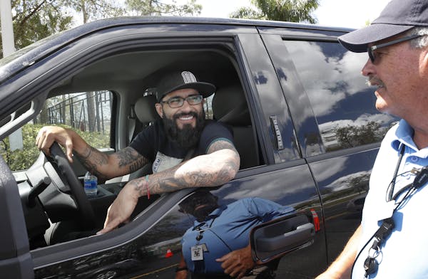Minnesota Twins pitcher Sergio Romo stops to say goodbye to parking operations worker Bill Fear, as he drives out of Hammond Stadium, Saturday, March 