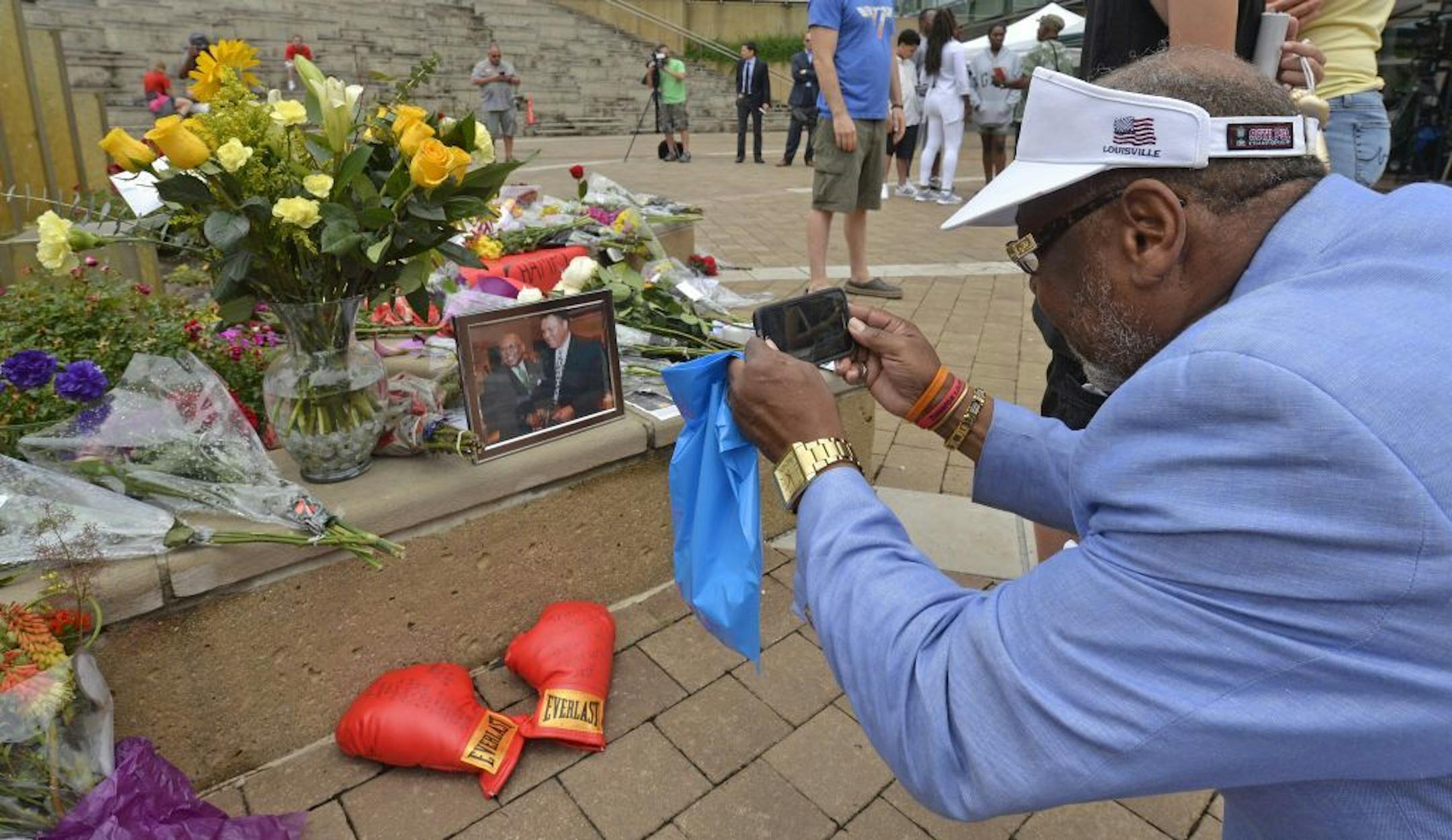 Frank Green, of Louisville, Ky., takes a photograph of a memorial for Muhammad Ali at the Muhammad Ali Center, Saturday, June 4, 2016 in Louisville Ky. Ali, the magnificent heavyweight champion whose fast fists and irrepressible personality transcended sports and captivated the world, has died according to a statement released by his family Friday, June 3. He was 74.