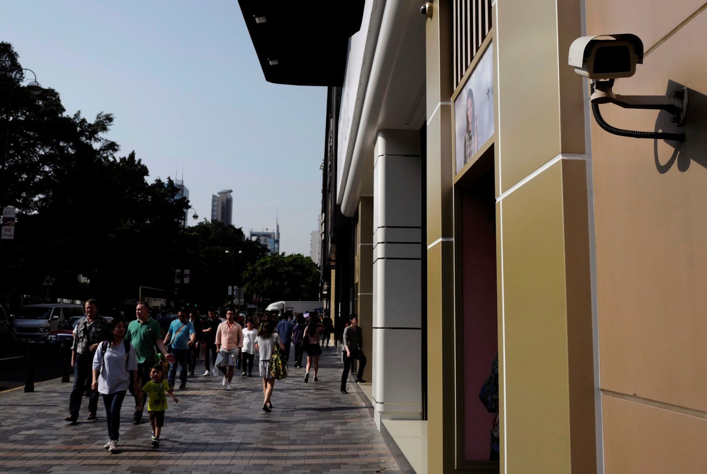 People walk near a surveillance camera on a main street in Hong Kong Tuesday, April 18, 2017. (AP Photo/Vincent Yu) ORG XMIT: XVY104