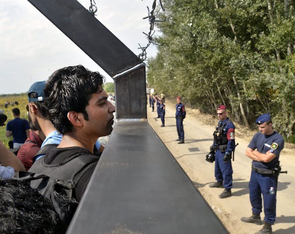 Migrants look through the border fence between Serbia and Hungary, near Horgos, Serbia, Tuesday, Sept. 15, 2015. Hungary has declared a state of emerg
