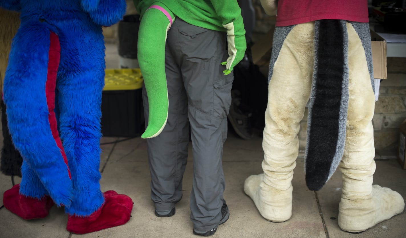 Fursuiters congregated around a table at the MN Furs' spring picnic .