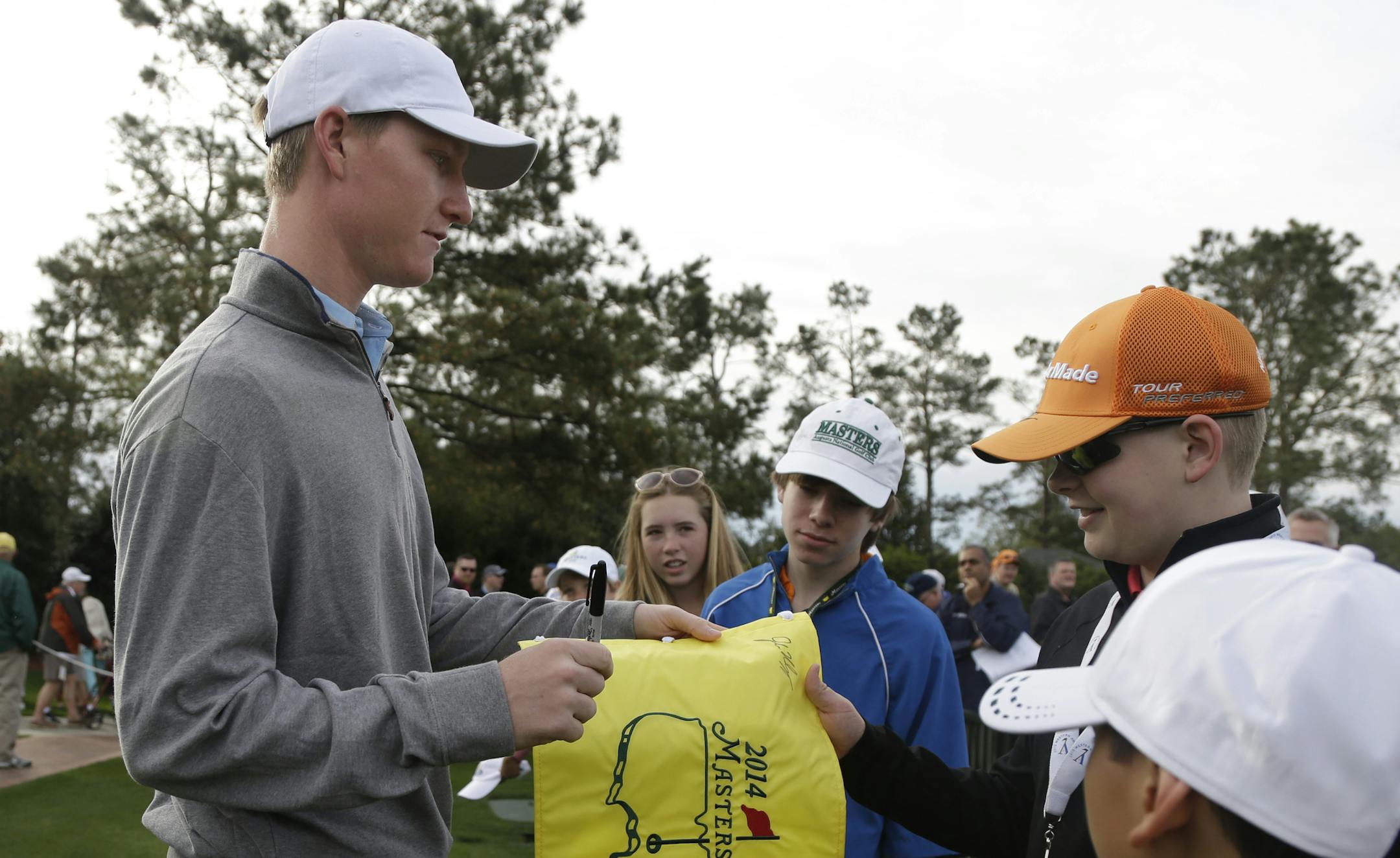Jordan Niebrugge signs autographs for young spectators during a practice round for the Masters golf tournament Tuesday, April 8, 2014, in Augusta, Ga. (AP Photo/Darron Cummings)