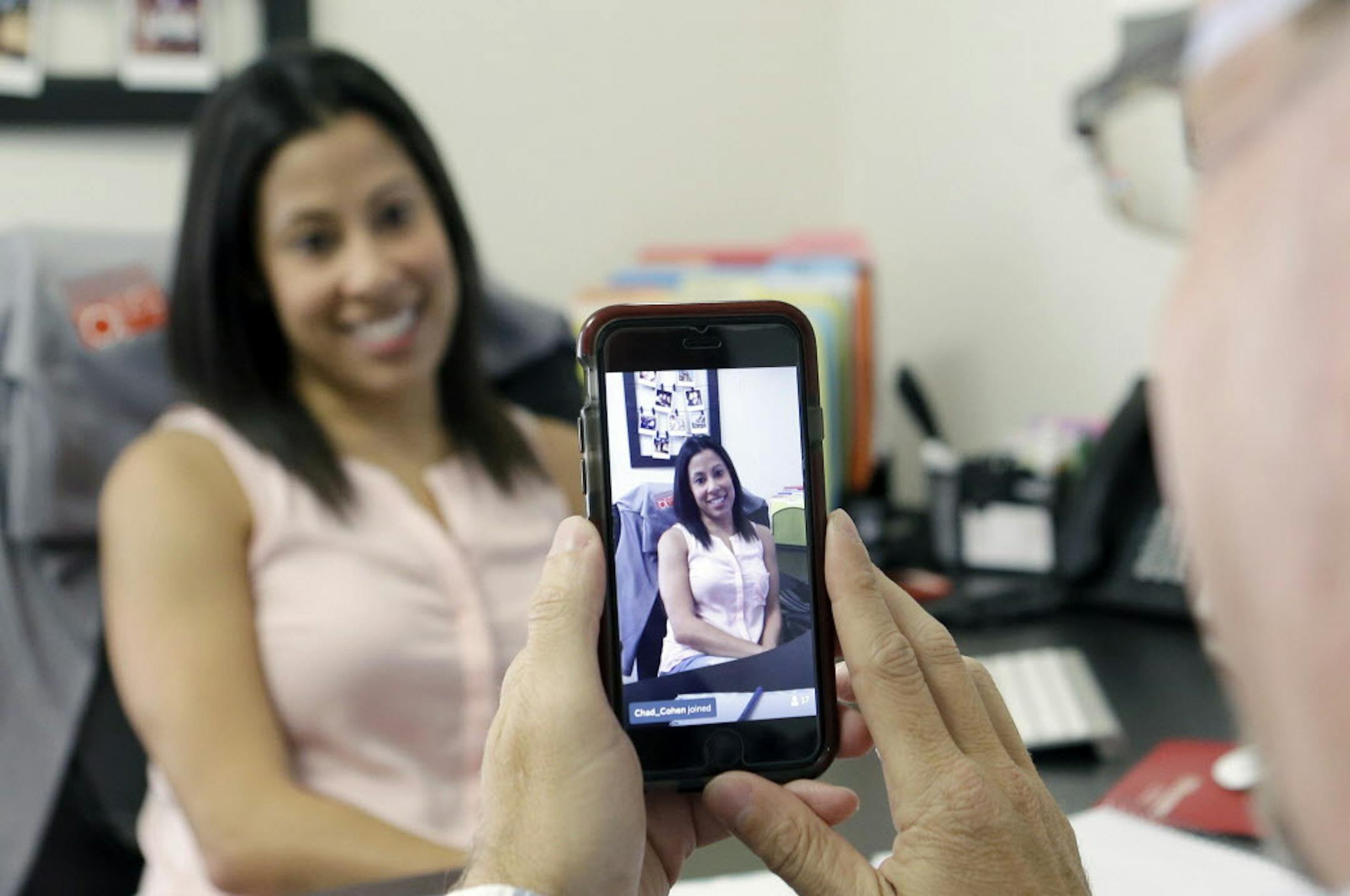 In this June 29, 2015, photo, Lauren Simo, left, answers questions during a weekly forum streamed via Periscope on the smartphone of Fish Consulting director of social media Toby Srebnik, at the company's offices in Hollywood, Fla. Marketing successes with Facebook, Twitter, Pinterest and Instagram have encouraged companies to try streaming apps like Periscope and Meerkat. (AP Photo/Alan Diaz)