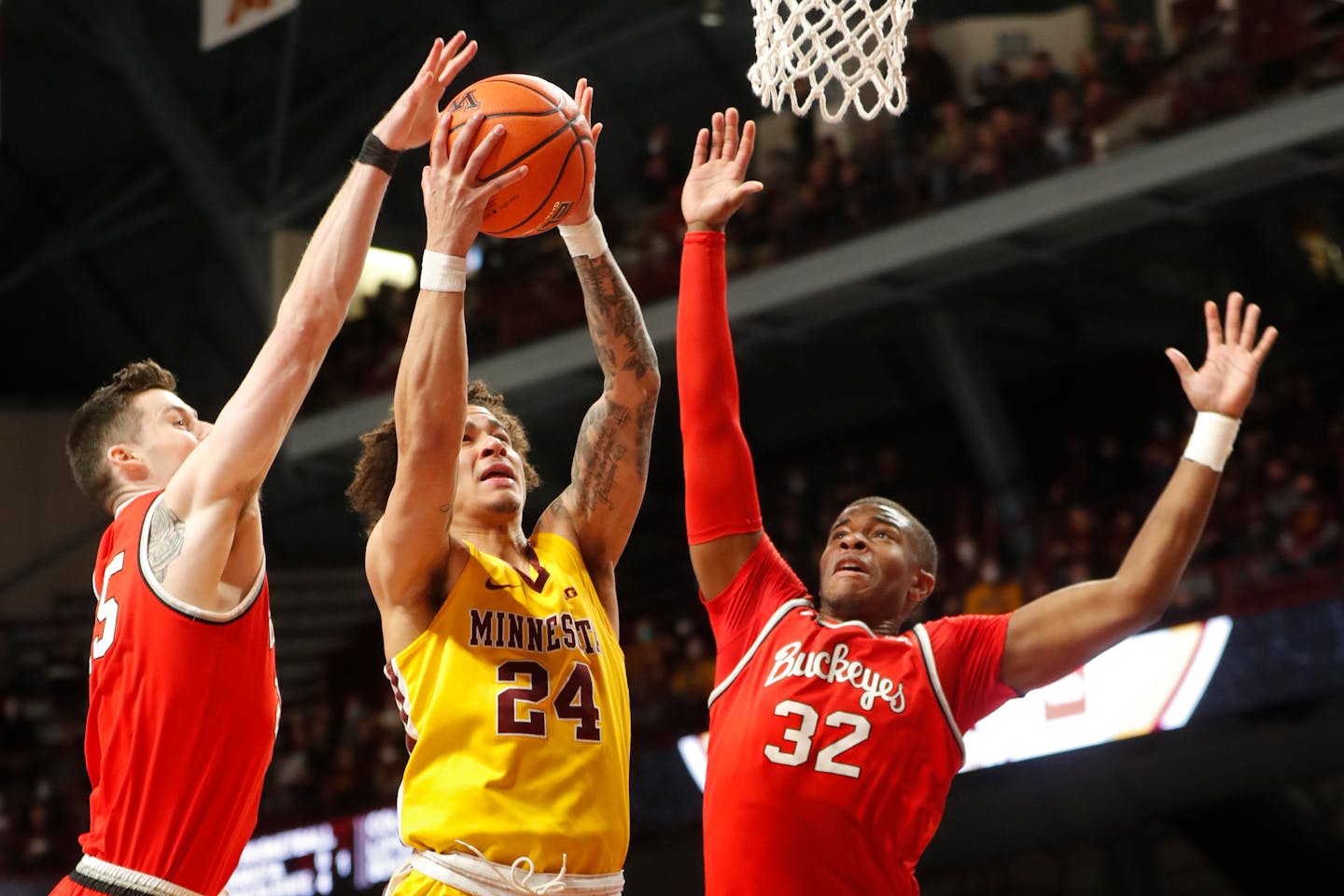 Gophers guard Sean Sutherlin shoots between Ohio State's Kyle Young (25) and E.J. Liddell (32) in the first half Thursday at Williams Arena.