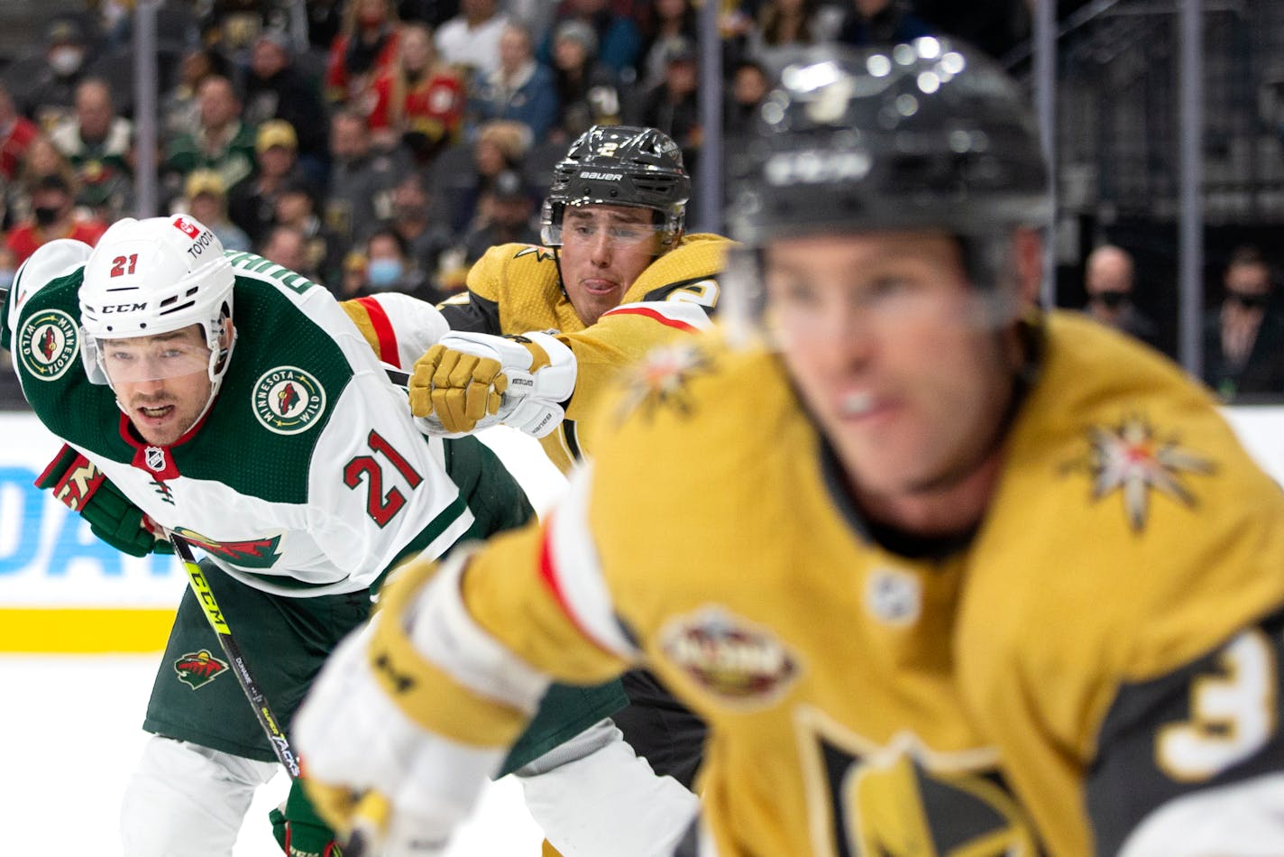 Vegas Golden Knights defenseman Zach Whitecloud, center, collides with Minnesota Wild right wing Brandon Duhaime (21) while Vegas Golden Knights defenseman Brayden McNabb, right, skates for the puck during the third period of an NHL hockey game Sunday, Dec. 12, 2021, in Las Vegas. (AP Photo/Ellen Schmidt)