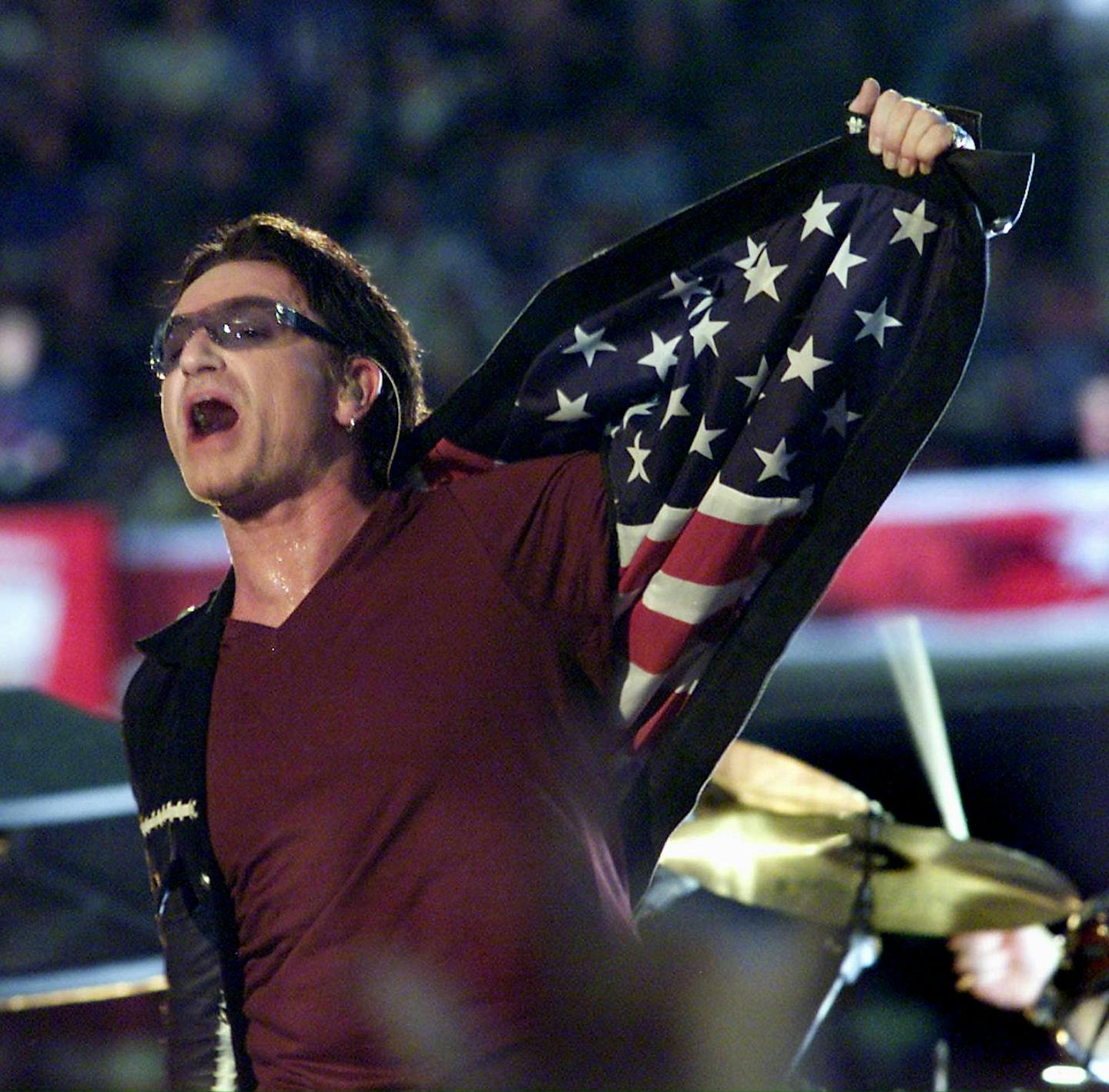 Bono, singer with the Irish rock group U2, opens his jacket exposing an American flag as he performs during halftime 03 February, 2002 of Super Bowl XXXVI in New Orleans, Louisiana. The St. Louis Rams and the New England Patriots are playing for the NFL championship. AFP PHOTO/Jeff HAYNES