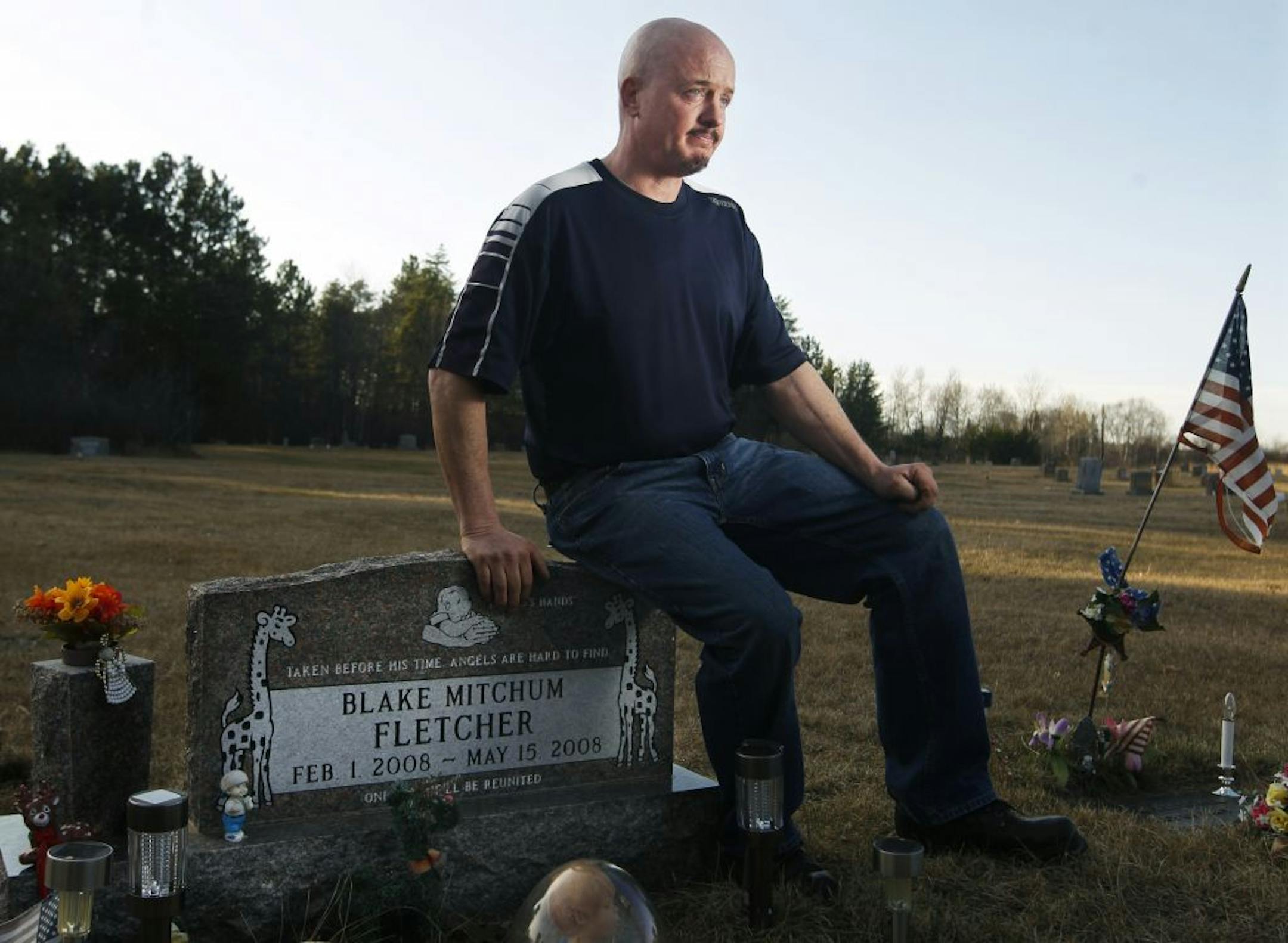 At the Green Valley Township Cemetery on 3/21/12, Robert Fletcher sat on the tombstone of his son, Blake who was 3.5 months old who died in the morning on the first day of attending daycare. He tries to visit the grave site every week. The cause of death is undetermined but a contributing factor was being placed face down in a playpen.
