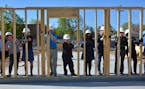 Shena Idoko (center, blue dress) worked with a Habitat for Humanity construction crew of volunteers and professionals this month to erect a wall of Id