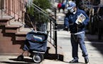 A United States Postal worker makes a delivery with gloves and a mask in Philadelphia, Thursday, April 2, 2020. The U.S. Postal Service is keeping pos