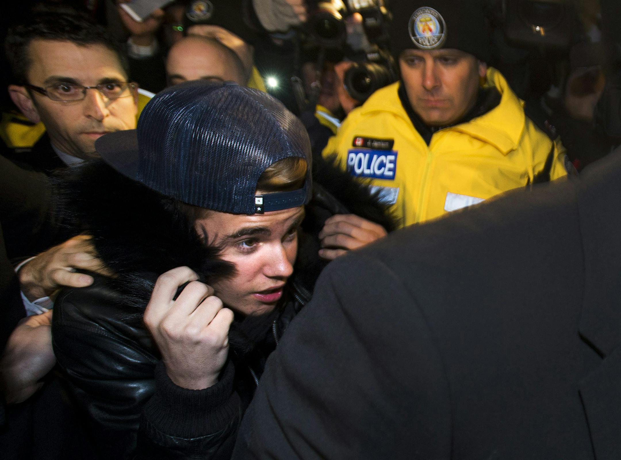 Canadian musician Justin Bieber is swarmed by media and police officers as he turns himself in to city police for an expected assault charge, in Toronto, on Wednesday, Jan. 29, 2014.