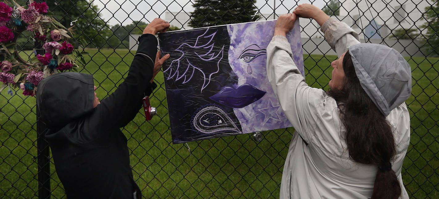 Mary Nye and Laura Menard hung artwork on the fence at Paisley Park in Chanhassen.