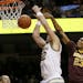 Michigan forward Ricky Doyle (32) loses control of the ball as he is fouled by Minnesota forward Charles Buggs (23) during the first half of an NCAA c