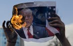Palestinian protesters burn a poster with a picture of President Trump during clashes with Israeli troops following protests against U.S. President Do
