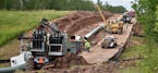 In this July 25, 2017, photo provided by Wisconsin Public Radio, crews begin work on the Wisconsin segment of Enbridge Energy's Line 3 near Superior, 