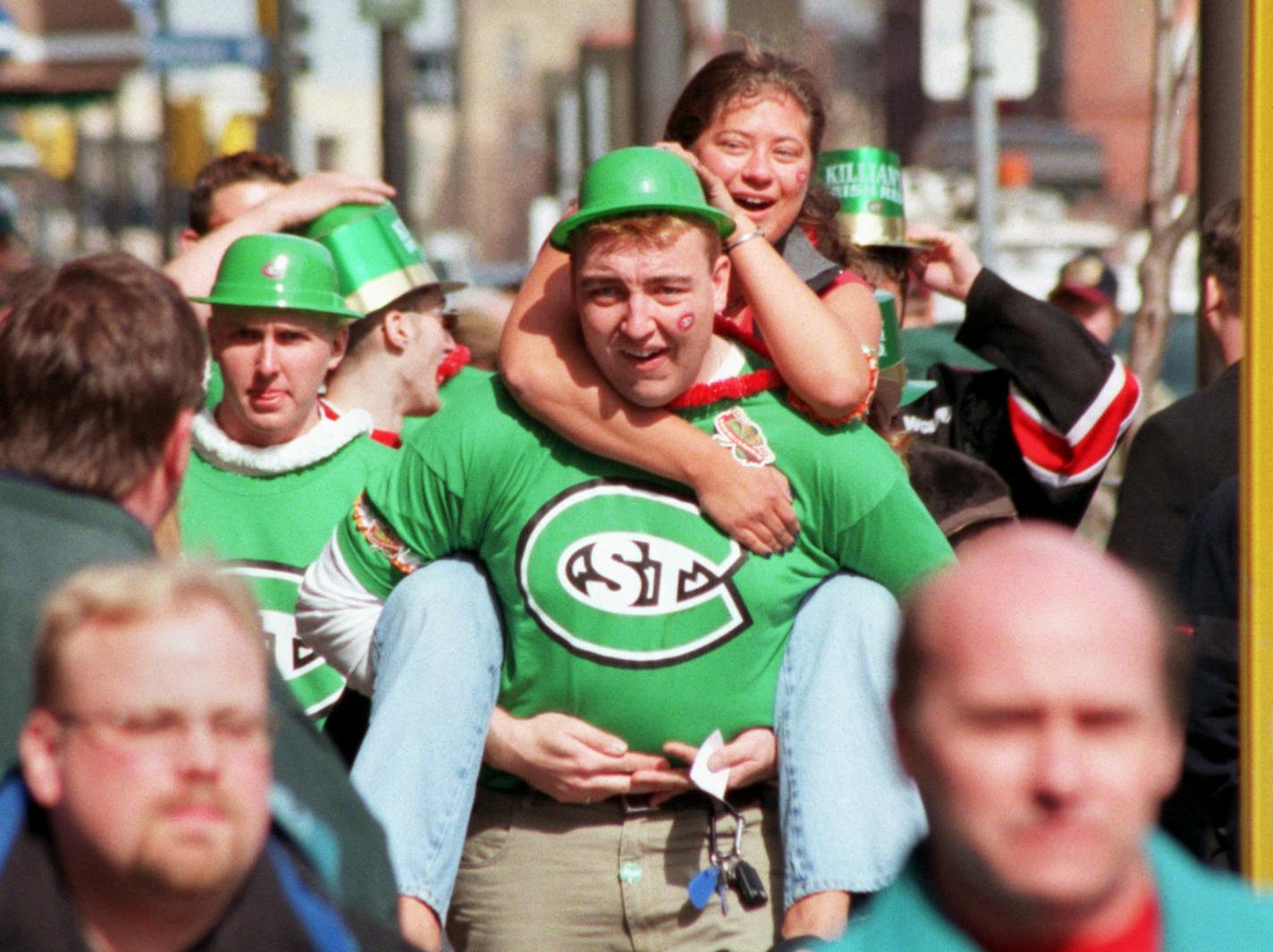 Minneapolis, MN. Friday 3/17/2000 The city is full of visitors attending the state high school girls baskeyball tourney, the WCHA hockey games , the NCAA basketball playoffs, and it is St. Patricks day. -- Members of the &#xce;dog pound&#xcc; a cheering section for the Saint Cloud hockey team, combined a St. Patricks day theme with their support for their hockey team as they traveled along 1st Av No en route to the 2 pm game at Target Center. In the center is Tim Bauman, and riding on his back i