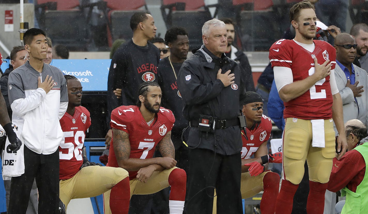 San Francisco 49ers quarterback Colin Kaepernick (7) kneels next to outside linebacker Eli Harold (58) and safety Eric Reid, right rear, during the national anthem before an NFL football game against the New England Patriots in Santa Clara, Calif., Sunday, Nov. 20, 2016. (AP Photo/Marcio Jose Sanchez) ORG XMIT: MIN2016112215255027