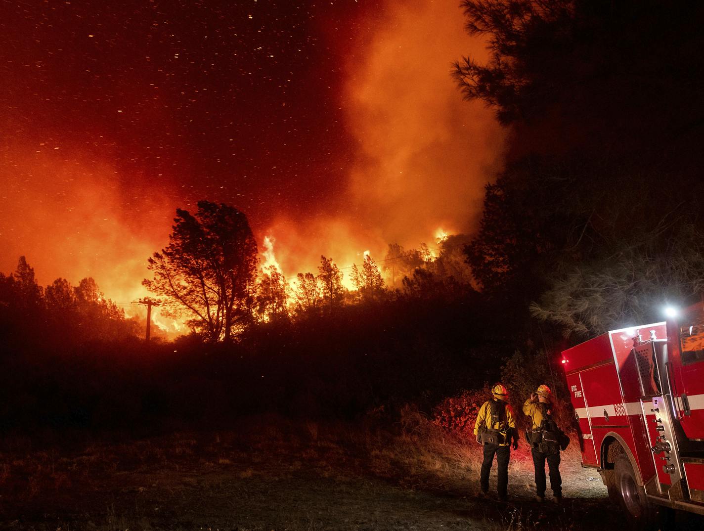 Firefighters watch the Bear Fire approach in Oroville, Calif., on Wednesday, Sept. 9, 2020. The blaze, part of the lightning-sparked North Complex, expanded at a critical rate of spread as winds buffeted the region.They work 50 hours at a stretch and sleep on gymnasium floors. Exploding trees shower them with embers. They lose track of time when the sun is blotted out by smoke, and they sometimes have to run for their lives from advancing flames. Firefighters trying to contain the massive wildfi