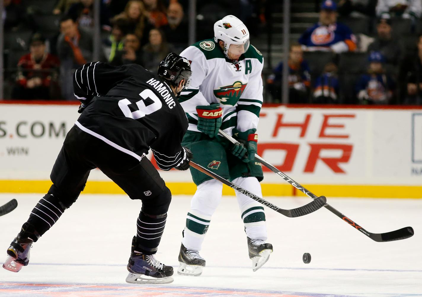 Minnesota Wild left wing Zach Parise (11) defends as New York Islanders defenseman Travis Hamonic (3) passes the puck during the third period of an NHL hockey game in New York, Tuesday, Feb. 2, 2016. The Islanders defeated the Wild 5-3. (AP Photo/Kathy Willens)