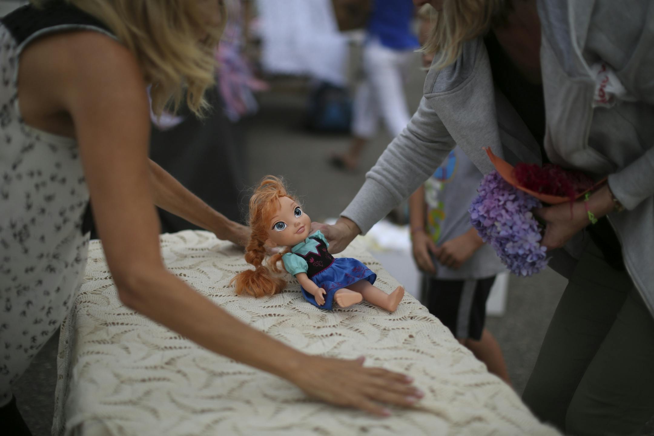 Volunteers set up a table with an Elsa doll from the movie "Frozen" as they prepared for the vigil for Alayna Ertl Tuesday night in the parking lot of St. Anthony Church in Watkins.