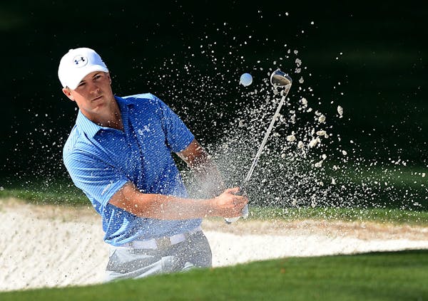 Jordan Spieth chips out of a bunker at the 10th green during the third round of the Masters at Augusta National Golf Club on Saturday, April 11, 2015,