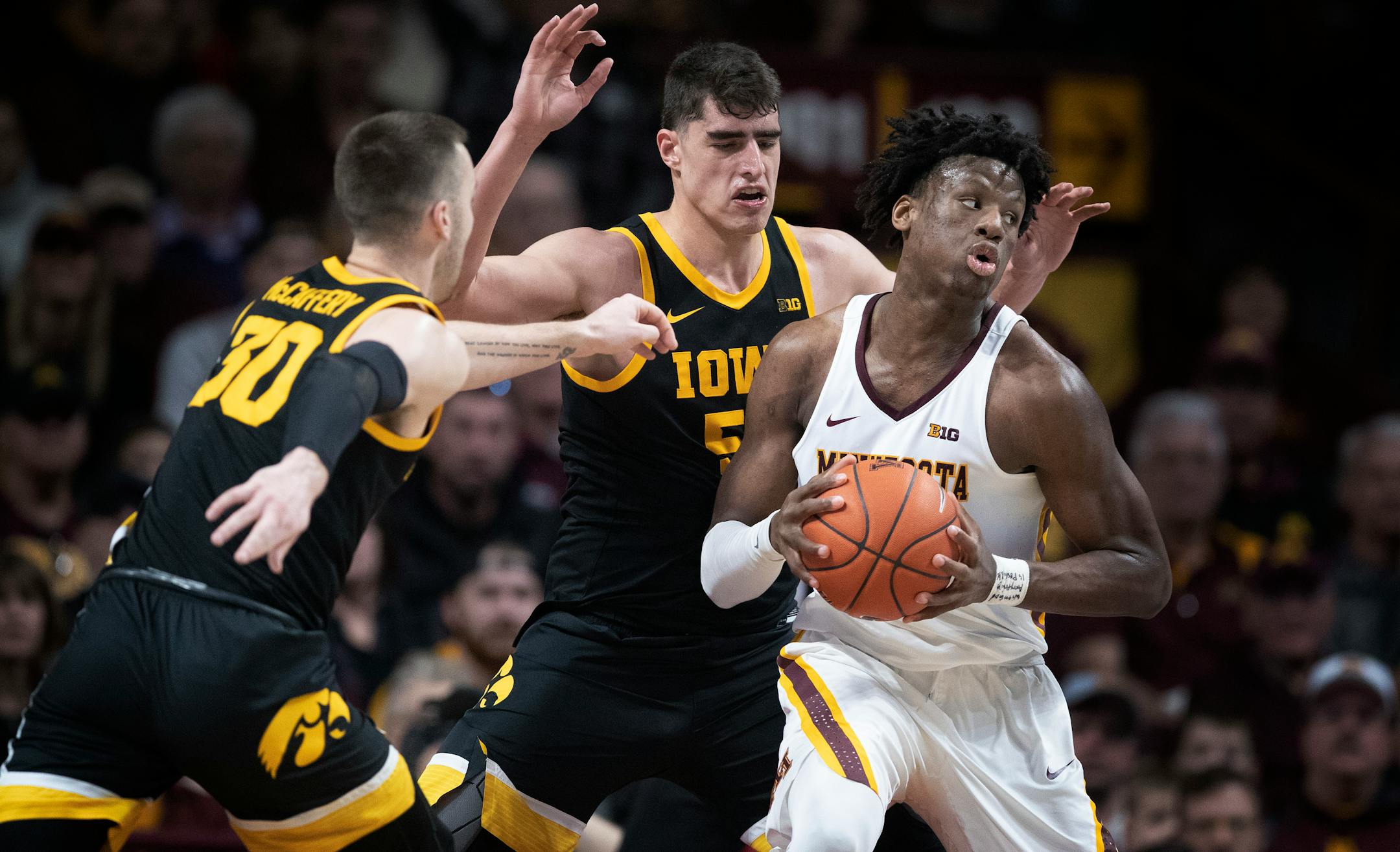 Gophers center Daniel Oturu was pressured by Iowa guard Connor McCaffery (30) and center Luka Garza (55).