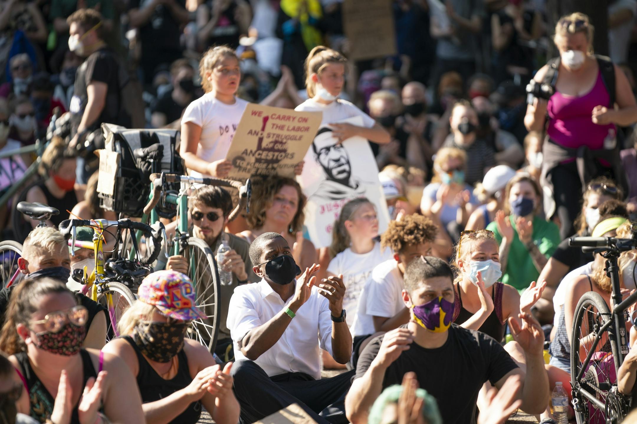 St. Paul Mayor Melvin Carter listened to one of the speakers, activist and writer Mel Reeves, while seated with the large crowd on Summit Ave.