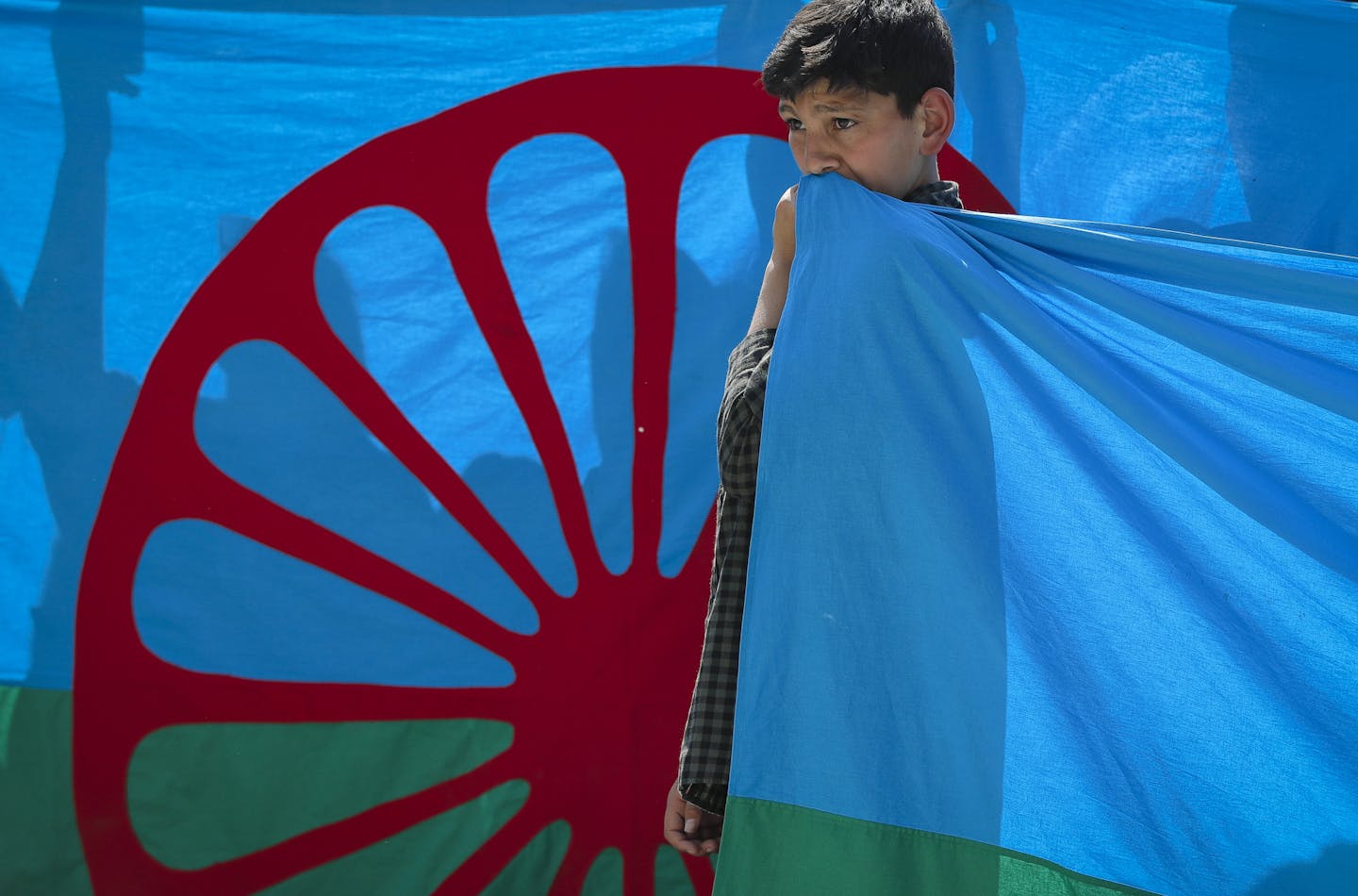 A boy holds a Roma flag during an anti-racism march by members of the Romanian Roma community celebrating the Romani Resistance Day in Bucharest, Romania, Saturday, May 18, 2019. On May 16, 1944 Roma prisoners in the Auschwitz concentration camp resisted an attempt by the Nazi troops to liquidate their camp, which postponed the action until August the same year. (AP Photo/Vadim Ghirda)