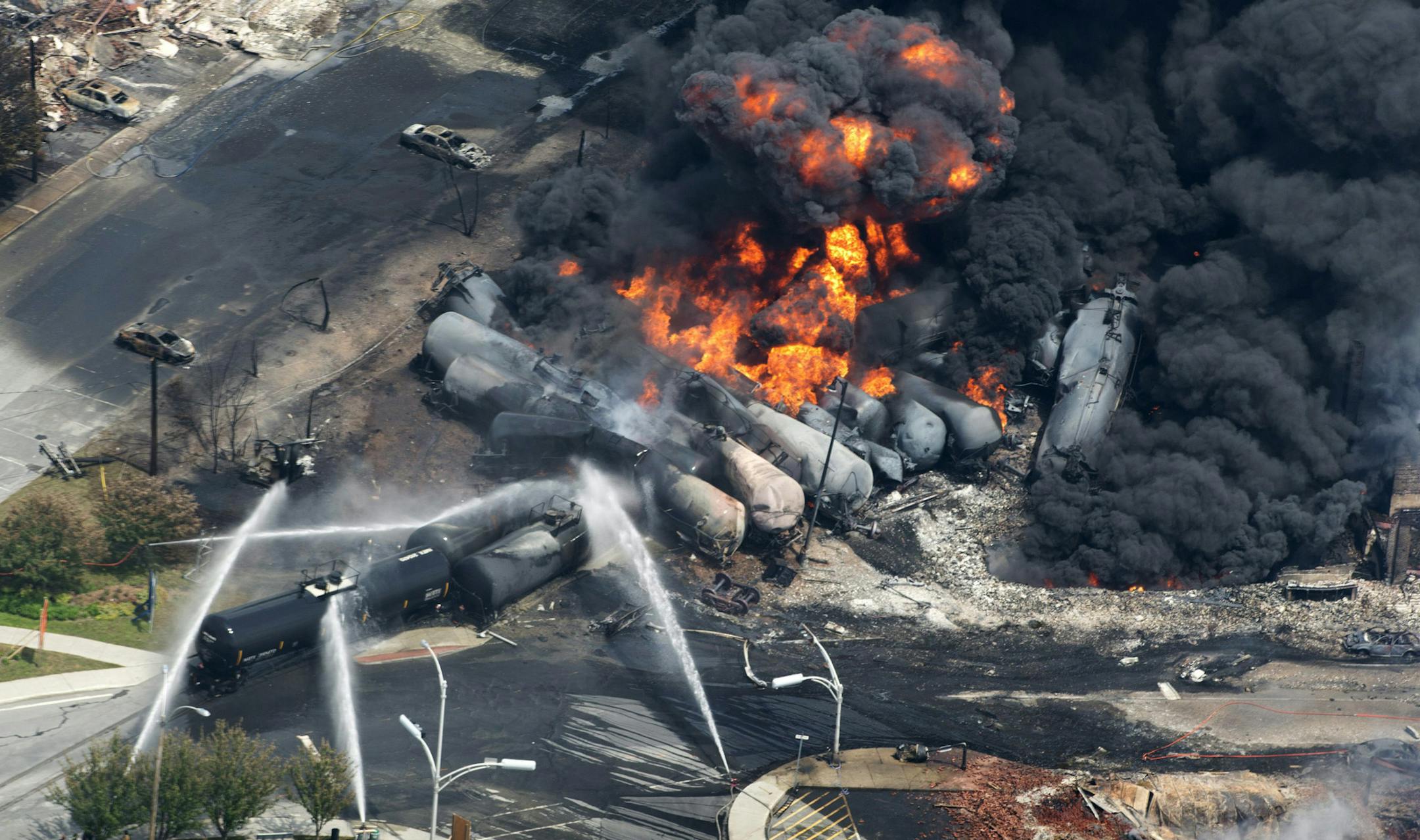 FILE - In this July 6, 2013 photo, smoke rises from flaming railway cars that were carrying crude oil after it a train derailed in downtown Lac Megantic, Quebec, Canada. A large swath of the town was destroyed after the derailment, sparking several explosions and fires that claimed 47 lives. John Giles, top executive of Central Maine and Quebec Railway, that purchased the railroad responsible for the derailment, said Friday, May 16, 2014 that they plan to resume oil shipments after track safety